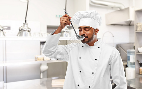 烹饪,职业人的快乐的印度男厨师品尝食物瓢餐厅厨房背景快乐的印度厨师厨房用勺子品尝食物图片