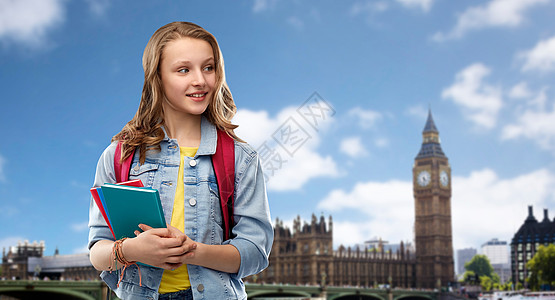 教育,学校人的快乐的微笑十几岁的学生女孩带着包书大本伦敦市的背景带着书包的快乐微笑的十几岁的学生女孩图片