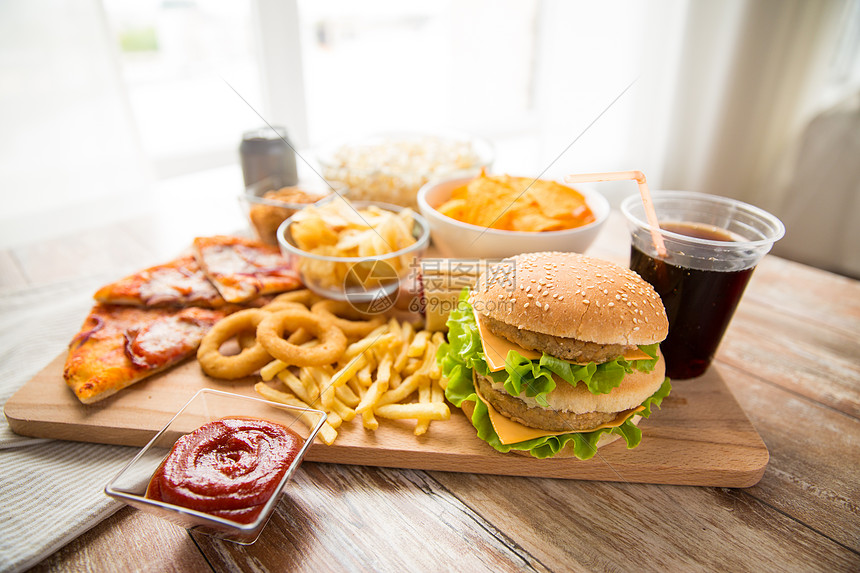 快餐健康的饮食双汉堡奶酪汉堡,油炸鱿鱼圈,炸薯条,比萨饼可乐饮料木板上桌子上快餐可乐饮料图片