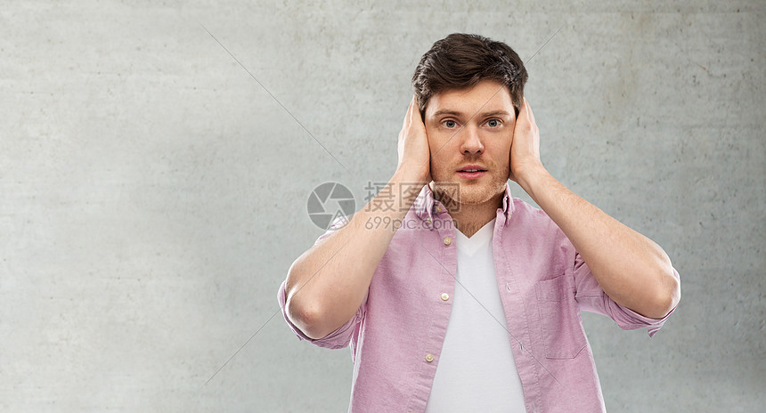 人,噪音压力的人耳朵手灰色背景男人用手把耳朵关灰色的混凝土墙上图片