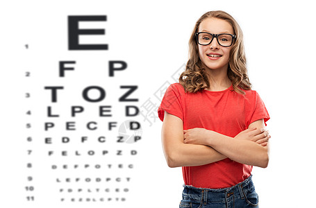 视觉,视力眼镜微笑的十几岁学生女孩戴着眼镜红色T恤,交叉手臂眼睛测试图表背景上戴眼镜的十几岁女孩超过了眼睛测试图图片