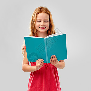 童人的微笑的红头发女孩阅读书灰色的背景微笑的红头发女孩看书图片