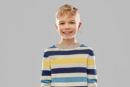 童,表情人的微笑的小男孩灰色背景上的条纹套头衫穿着条纹套衫的微笑男孩的肖像图片