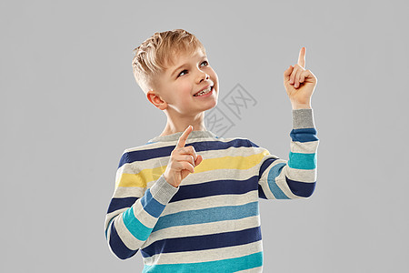 童,表情人的小男孩穿着条纹套头衫,手指指向灰色背景穿条纹套衫的小男孩指着手指图片