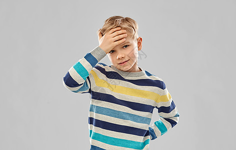 童,表情人的生病的小男孩穿着红色马球T恤,灰色背景下头痛穿着红色T恤的生病男孩头痛图片