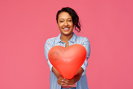 情人节人们的快乐的非裔美国轻妇女与红色心形气球粉红色的背景带心形气球的非裔美国妇女图片