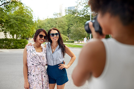 女友谊,技术人女人用相机拍摄她的朋友夏季公园女人夏季公园给她的朋友拍照图片