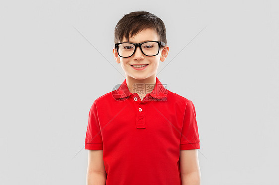 学校,教育视觉微笑的小男孩穿着红色马球T恤,戴着灰色背景的眼镜戴眼镜红色T恤的微笑男孩的肖像图片