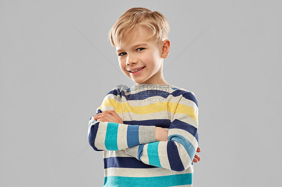 童,表情人的微笑的小男孩穿着条纹套衫,交叉手臂灰色背景上带交叉手臂的条纹套衫微笑的男孩图片