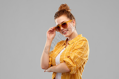 夏天,眼镜人的微笑的红头发少女戴着太阳镜黄色格子衬衫,交叉手臂灰色背景上戴着太阳镜微笑的红头发少女图片