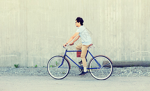 轻的时髦男子骑固定齿轮自行车图片