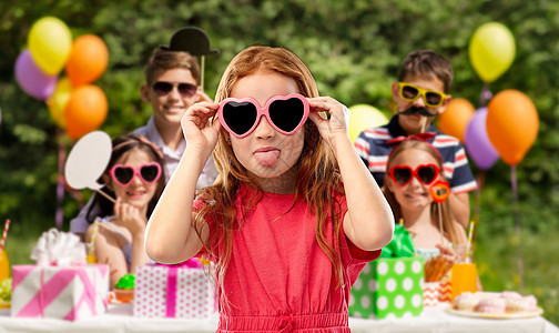 童,情人节夏天的淘气的红头发女孩与心形太阳镜舌头生日聚会公园淘气的红头发女孩戴着心形太阳镜图片