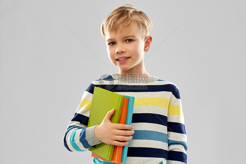 学校,教育人的小学生男孩的肖像与书籍灰色背景带书的小学生男孩图片