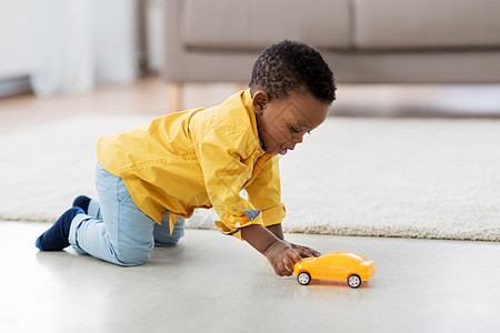 童,孩子人的可爱的非裔美国男孩玩黄色玩具汽车地板上家里非裔美国小男孩玩玩具车图片