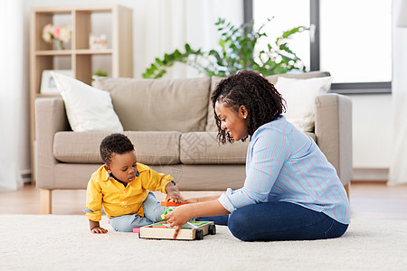 童,孩子人的快乐的非裔美国母亲她的小儿子玩木制玩具积木套件地板上家里妈妈宝宝家玩玩具积木图片