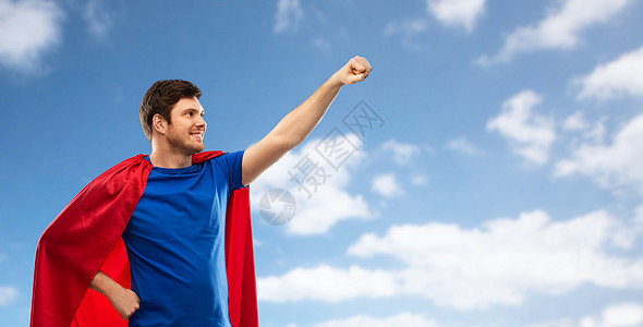 超级力量人的快乐的轻人红色超级英雄披风蓝天云背景穿着红色超级英雄斗篷的男人天空背景上图片