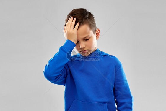 童,表情人的生病的男孩Slue帽衫遭受头痛的灰色背景穿着Slue帽衫的生病男孩头痛图片