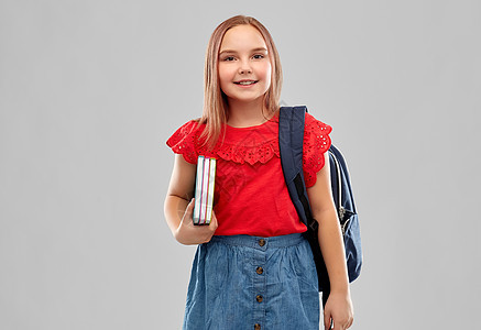 学校,教育童的美丽的微笑学生女孩穿着红色衬衫裙子,带着灰色背景的书籍袋子带着书包微笑的学生女孩图片