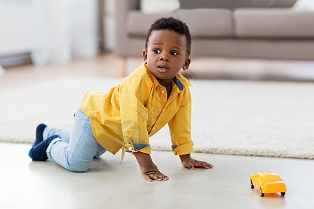 童,孩子人的可爱的非裔美国男孩玩黄色玩具汽车地板上家里非裔美国小男孩玩玩具车图片