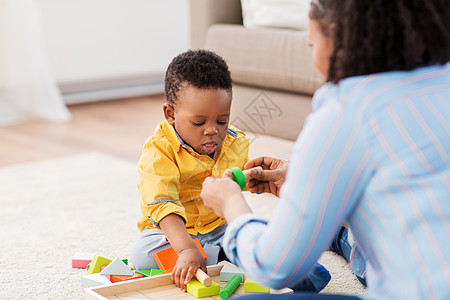 童,孩子人的非裔美国母亲她的小儿子玩木制玩具积木套件地板上家里妈妈宝宝家玩玩具积木图片