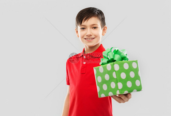 生日,童人的微笑的小男孩穿红色马球T恤,礼品盒灰色背景带生日礼物盒的红色T恤微笑的男孩图片