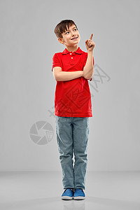 童,表情人的小男孩穿着红色马球T恤,手指指向灰色背景穿着红色马球T恤的小男孩指着手指图片