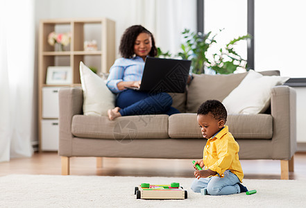 家庭,母亲人的非裔美国人婴儿玩玩具积木套件他的母亲用笔记本电脑家婴儿玩玩具积木母亲用笔记本电脑图片