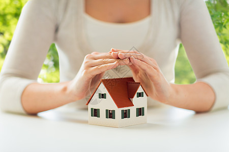安全家庭保险的密切妇女保护房子的模式,手中的绿色自然背景用手保护房子模型的女人图片