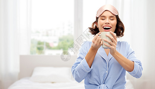 人们睡前的快乐的轻女人睡衣眼罩喝咖啡杯子背景女人睡衣睡觉的具喝咖啡图片