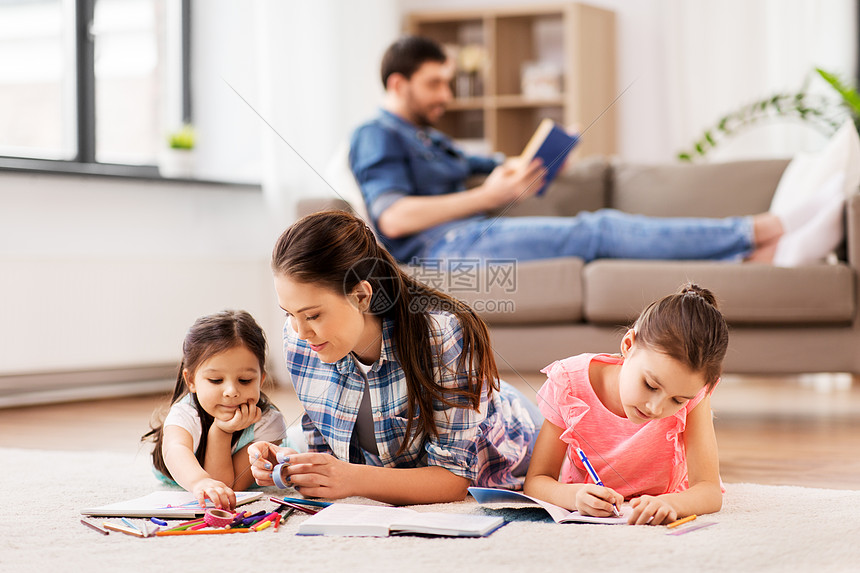 家庭母亲休闲母亲花时间她的小女儿素描簿上用蜡笔画画,躺家里的地板上母亲带着小女儿家画画图片