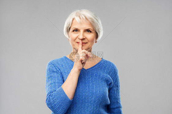 灰色背景下的老年女性表示嘘声的手势图片