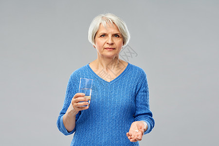 老妇女拿着杯水药丸吃药图片