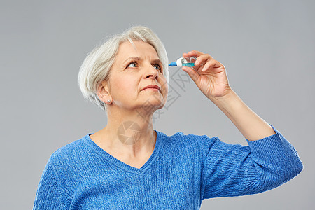 医学,健康视力人的老妇女干眼综合征的肖像用滴灰色背景上老妇女干眼综合征用滴剂图片