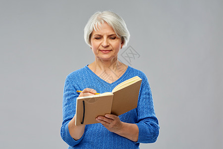 穿蓝色毛衣的老年妇女在写日记图片