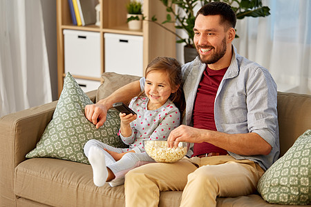 家庭,父亲人的快乐的父亲女儿带着爆米花遥控器家看电视快乐的父亲女儿家看电视图片