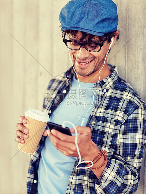 人技术休闲生活方式城市街道上用耳机智能手机喝咖啡听音乐的快乐微笑的人带着耳机智能手机的男人喝咖啡图片