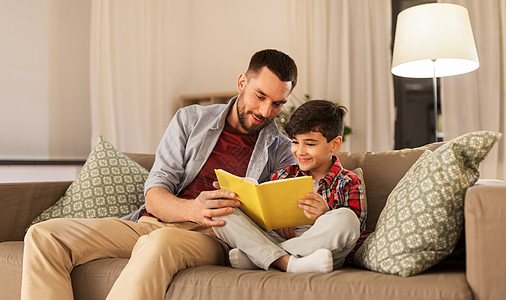 家庭,童,父爱,休闲人的快乐微笑的父亲小儿子家里沙发上看书快乐的父子家看书沙发图片