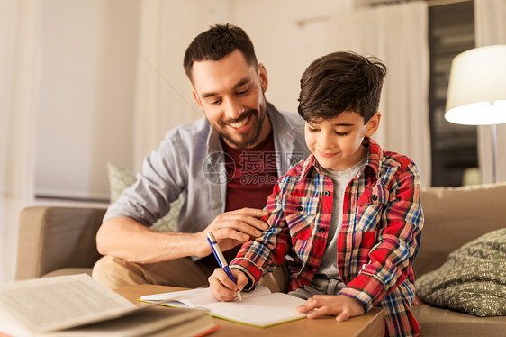 教育,家庭家庭作业的快乐的父亲儿子家里写书笔记本父亲儿子作业图片