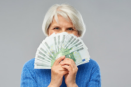 储蓄金融人的老年女子躲百欧元钞票的粉丝后数百欧元钞票的高级女人图片