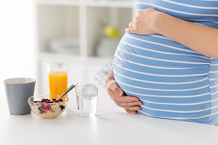 怀孕,健康饮食产妇密切孕妇与早餐厨房桌子上触摸她的肚子家里靠近孕妇抚摸她的腹部图片