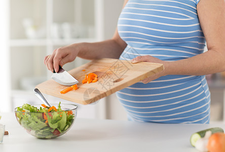 怀孕,烹饪食物健康饮食密切孕妇与菜刀添加切碎胡椒木制切割板沙拉碗家里孕妇家烹饪食物图片