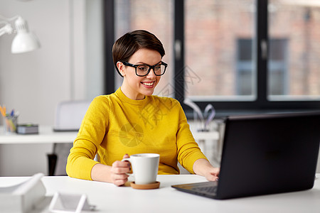 商业,休息人的女商人戴着眼镜,带着笔记本电脑办公室喝咖啡女商人办公室着笔记本电脑喝咖啡图片