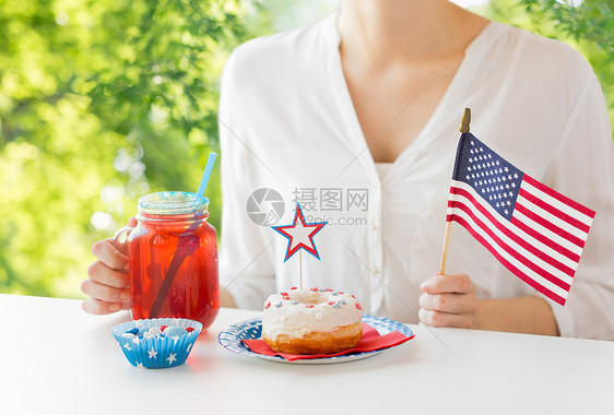 独立日,庆祝节日的妇女吃釉甜甜甜圈,喝果汁大璃梅森罐杯子7月4日自然夏季绿色背景庆祝美国独立日的女图片