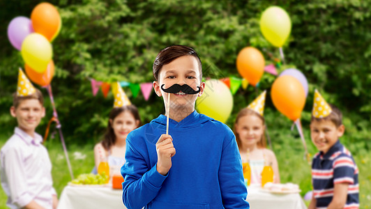 派道具,照片亭童的微笑男孩穿着蓝色帽衫,黑色胡子群朋友的生日夏季公园背景生日聚会上留着黑色胡子的快乐男孩图片