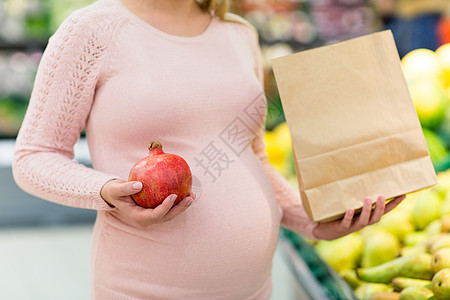 购物食物怀孕杂货店超市买石榴的孕妇用纸袋特写孕妇带着袋子杂货店买水果图片