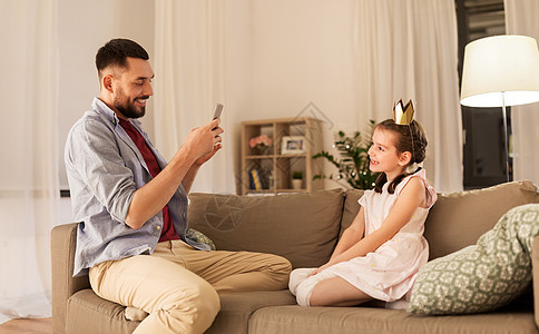家庭,技术人的快乐的父亲家里用智能手机拍摄公主女儿父亲家用手机给女儿拍照图片