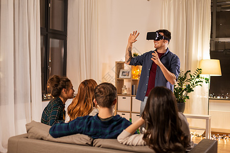 技术娱乐活动男人与虚拟现实耳机虚拟现实眼镜玩电子游戏家里男人戴着VR眼镜家朋友图片