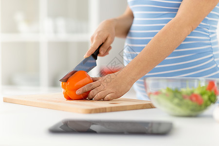 怀孕,烹饪食物健康饮食密切孕妇制作蔬菜沙拉切胡椒刀切割板家里厨房孕妇家煮蔬菜沙拉图片