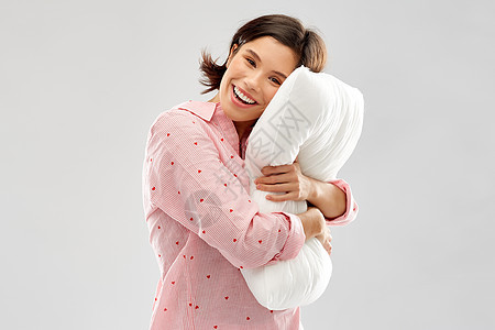 人们睡前的快乐的轻女人睡衣拥抱枕头灰色背景快乐的轻女人睡衣拥抱枕头图片