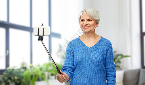 微笑的老年女人在智能手机自拍图片